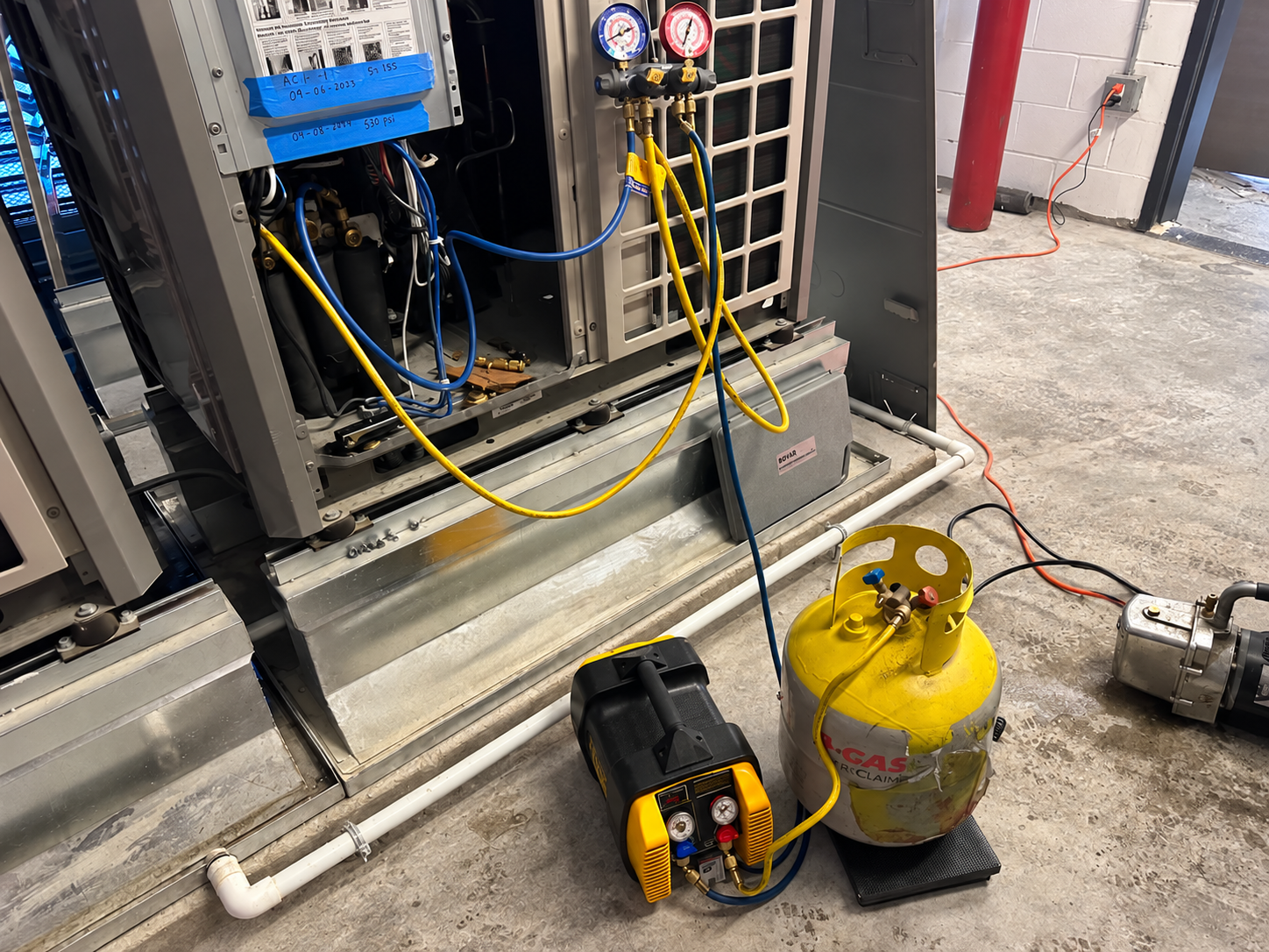 AI-retouched editorial view of an open HVAC unit with gauges, hoses and service equipment; background clutter removed